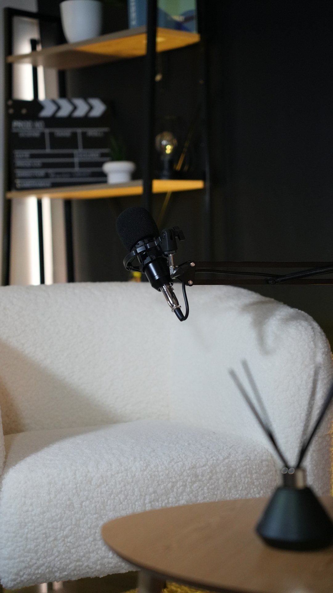 Microphone sur bras devant un fauteuil blanc en tissu bouclé